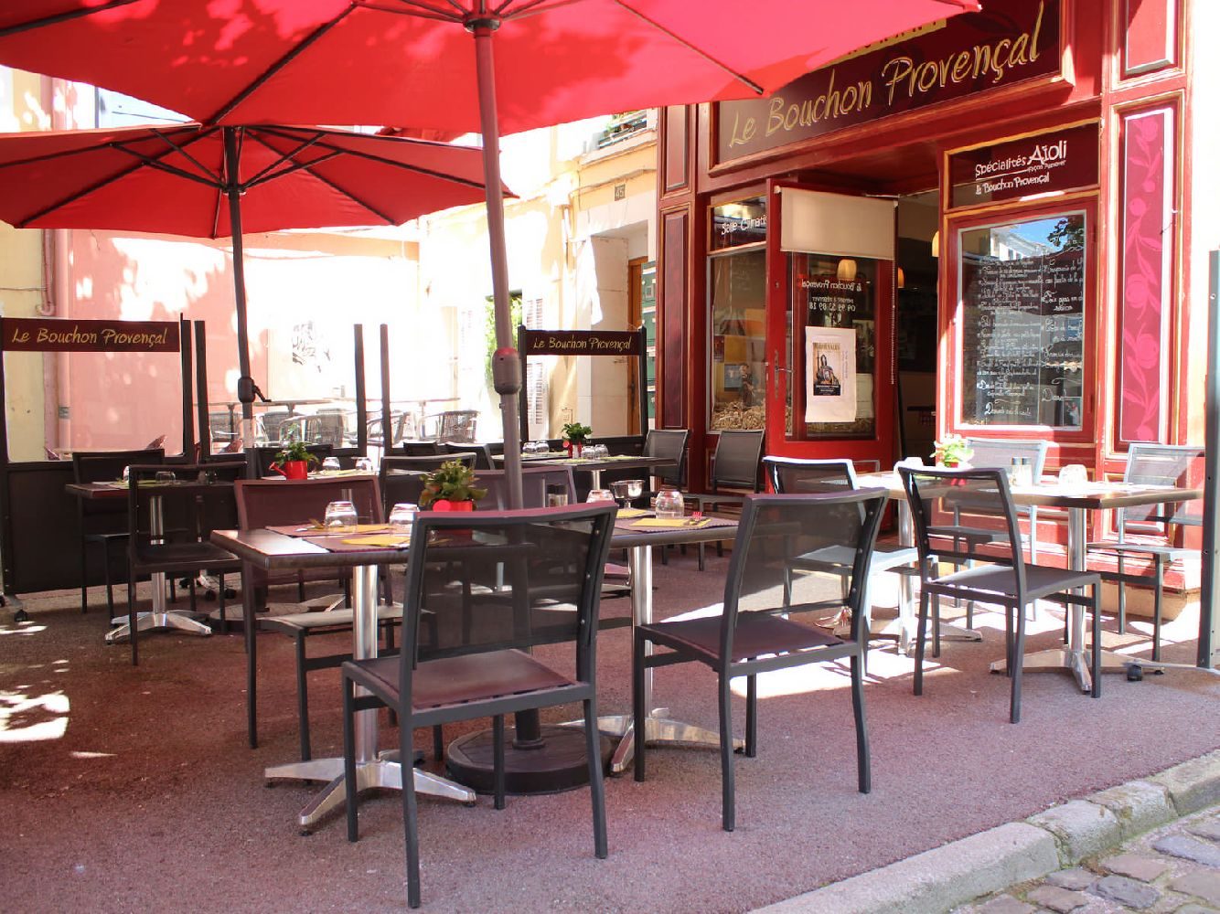 La terrasse et l'entrée du restaurant, sous les parasols rouges, dans la ruelle du vieux Saint-Raphaël